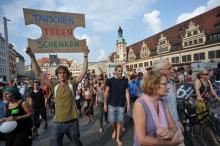 Menschen auf dem Marktplatz in Leipzig, die für Klimagerechtigkeit eintreten; Quelle: https://commons.wikimedia.org/wiki/File:Degrowth-2014-leipzig-demonstration-2-klimagerechtigkeit-leipzig.jpg